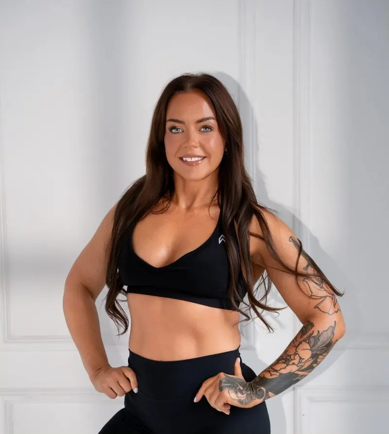 Fiona smiling, hands on hips, in front of a white panelled wall